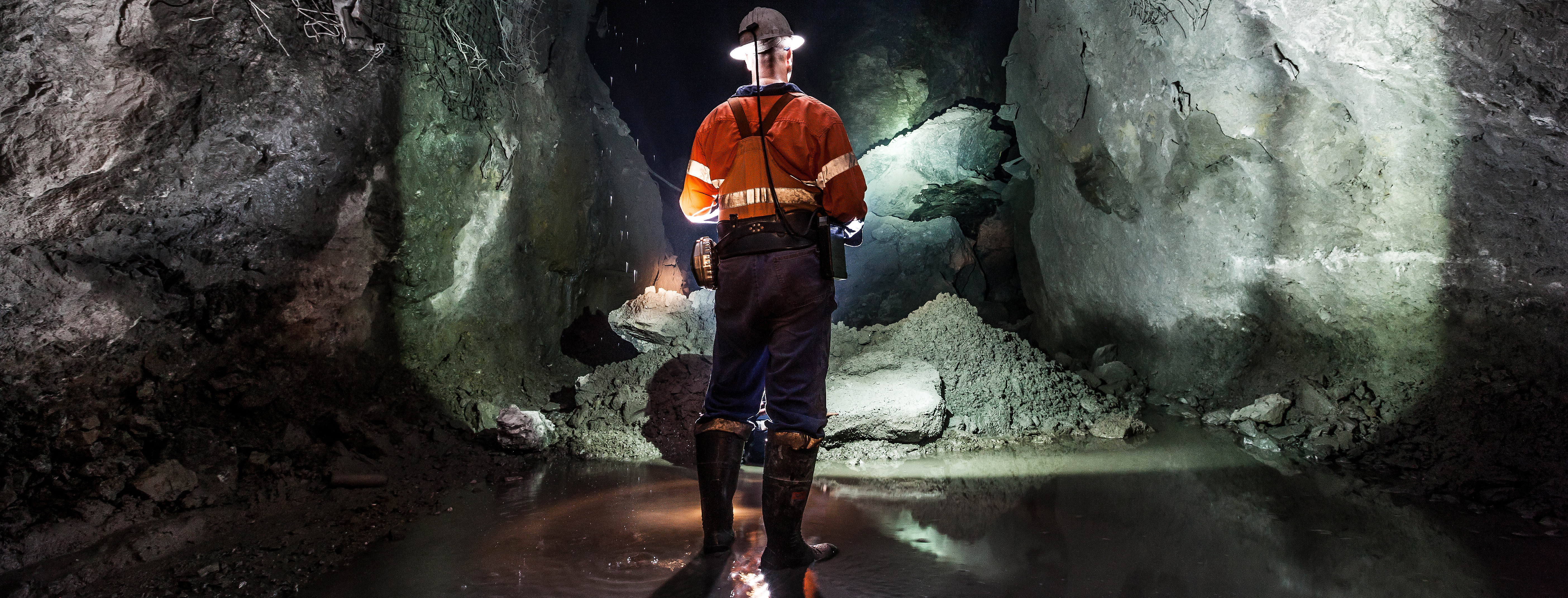 A miner inside a copper mine, standing in flooded water, emphasizing the critical role of mining pumps for effective mine dewatering.